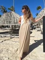 Vestido largo de tirantes, con corpiño en color blanco texturizado y falda larga en tono beige/dorado con brillo sutil. Presenta un escote en V profundo en el frente.