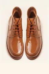 Bota acordonada de cuero vacuno con acabado charol color suela, con suela de goma tipo crepe y costuras reforzadas.