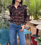 Camisa de algodón a cuadros en tonos marrón y negro, con diseño de volados en el frente, cuello clásico, cierre frontal con botones y mangas largas.