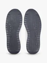 Zapatillas de estilo runner de Tommy Hilfiger, confeccionadas en una mezcla de cuero y textil en color blanco con detalles en gris claro y un panel amarillo en el talón. Presentan cordones blancos y suela de goma con base oscura.