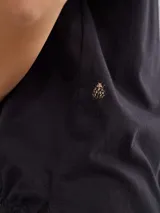 Remera blanca de algodón suave con detalle de bordado en los hombros y cordón ajustable en el ruedo.