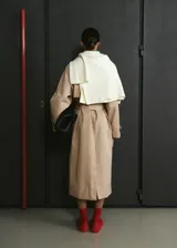 Gabardina larga color beige, de doble botonadura, con solapas amplias, mangas largas raglán, cinturón ajustable con hebilla y bolsillos laterales.