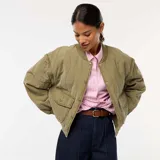 Chaqueta bomber acolchada color verde oliva, con cuello, puños y bajo acanalados. Presenta cierre frontal con botones a presión, bolsillos delanteros con solapa y mangas largas extraíbles.