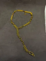 Collar corbatero dorado con diseño asimétrico que combina diferentes tipos de cadenas entrelazadas.