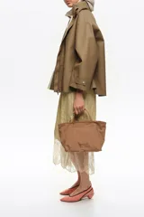Bolso shopper mediano de mano Bimba y Lola color marrón, confeccionado en poliamida con detalles en cuero y herrajes metálicos dorados. Cuenta con doble asa de mano, correa de hombro ajustable de lona beige, cierre superior con cremallera y logo impreso en dorado al frente.