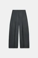 Pantalón wide leg de tiro medio color gris con raya diplomática, confeccionado en hilatura con viscosa. Cuenta con bolsillos laterales ocultos en costura, detalle de pinzas frontales y cierre con cremallera, botón y ganchos metálicos.
