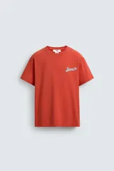 Camiseta de corte relajado con cuello redondo y manga corta. Presenta un estampado frontal con texto en contraste y un acabado con efecto lavado que le otorga una apariencia única.