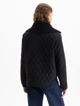 Campera matelaseada de corte recto y largo a la cadera, con cuello y puños de tejido acanalado. Presenta cierre frontal con broches grabados, bolsillos plaqué en el frente y cordón ajustable en el cuello.