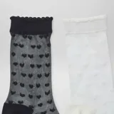 Pack de dos pares de medias de gasa semitransparente, una en color negro y otra en color blanco, ambas con diseño de corazones en relieve y terminación con borde fruncido.