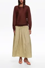 Falda midi de corte en A y silueta fluida, color beige, con diseño de frunces hasta la cadera que aporta movimiento.