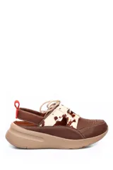 Zapato deportivo abierto en el talón, confeccionado en cuero liso marrón con detalles de cuero con pelo estampado tipo animal print en la parte superior. Presenta cierre con cordones, perforaciones decorativas en la puntera y una suela de plataforma color beige.