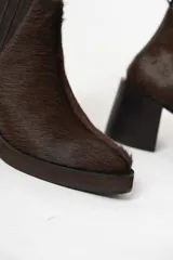 Botas Chelsea de cuero con pelo color marrón oscuro, con elásticos laterales y cierre interno. Taco bloque de madera y plataforma delantera.