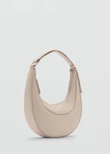 Bolso de hombro tipo media luna color beige, con cierre superior de cremallera y asa corta.