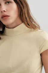 Vestido midi de gabardina en color beige, con cuello subido, manga corta y falda acampanada con caída fluida.