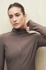 Campera deportiva de textura acanalada, color negro, con cierre frontal, cuello alto y mangas largas con orificio para el pulgar.