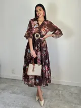 Vestido midi marrón de estilo campesino confeccionado en organdí, con estampado floral chintz. Presenta escote en V, cintura elastizada y mangas cortas con volados.