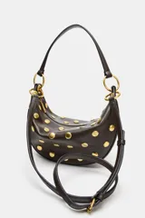 Bolso tipo hobo color marrón oscuro con tachas doradas distribuidas por todo el cuerpo. Cuenta con un asa de hombro y dos anillas metálicas doradas. El cierre es de cremallera metálica y tiene un bolsillo interior con cremallera.