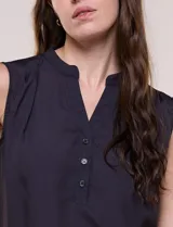 Blusa de gasa sin mangas de calce holgado, marca Sioni. Cuenta con cuello cadete, abertura frontal en V con media cartera de botones, espalda con canesú y pliegue central, y ruedo redondeado.