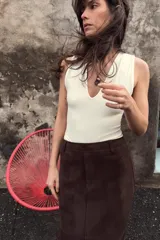 Body entallado color marrón oscuro con escote pronunciado en pico y manga sisa. Cierre en la parte inferior con botones a presión.