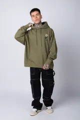 Buzo tipo canguro de corte oversize, color blanco, con capucha y cordones ajustables. Presenta un pequeño estampado de una rosa roja en el pecho y un bolsillo frontal tipo canguro.
