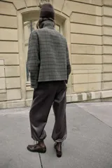 Pantalón de tiro alto confeccionado en material con efecto piel, con cintura elástica, bolsillos delanteros y nervio marcado en el frente. Presenta un diseño bombacho con bajo ajustable mediante cordones elásticos.