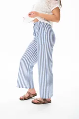 Pantalón largo a rayas verticales azules y blancas, con botón de coco, cintura elastizada y plizado en el bolsillo.