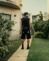 Tank top negro de corte boxy, sin mangas, con un estampado frontal en blanco que incluye una estrella con las letras "SK" en su interior y un punto.