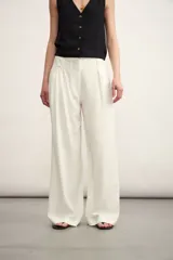 Pantalón de corte sastrero y tiro alto, con diseño de pierna ancha y pinzas frontales. Cuenta con bolsillos laterales y cierre frontal con botón oculto.