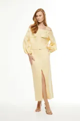 Falda midi color amarillo pálido, de corte recto con abertura frontal y cinturón con hebilla circular.