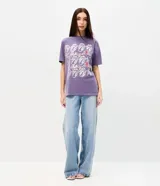 Remera de algodón color lila con efecto lavado, cuello redondo y mangas cortas. Presenta estampa frontal licenciada de The Rolling Stones con múltiples repeticiones del icónico logo de la lengua y detalles metalizados.
