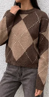 Sweater de punto con diseño de rombos en tonos marrones y beige, cuello redondo y mangas largas con puños acanalados.
