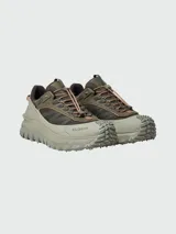 Championes de trail running Moncler modelo Trailgrip GTX, en tonos verde oliva y beige. Presentan un diseño robusto con suela dentada Vibram, sistema de cordones de ajuste rápido y refuerzo en la puntera con el logo de la marca.