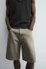 Bermuda de denim de algodón, color verde claro lavado, de corte recto y tiro medio. Presenta cinco bolsillos y cierre frontal con cremallera y botón.