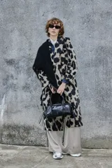 Tapado de corte recto y largo midi con estampado animal print de manchas grandes en tonos beige y negro. Presenta solapas clásicas, cierre frontal con botones y mangas largas.