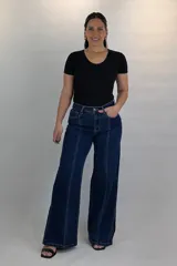 Pantalón wide leg de jean azul oscuro con costuras frontales marcadas y aberturas en los bajos.