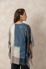 Blusa tipo túnica de gasa semitransparente con escote en V y mangas amplias. Presenta un diseño estampado con efecto acuarela en tonos azules, grises y marrones sobre fondo blanco.