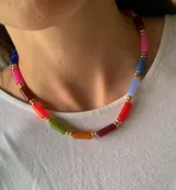 Collar corto tipo gargantilla compuesto por cuentas cilíndricas de colores variados intercaladas con pequeñas esferas doradas.