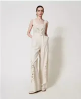 Mono largo de tejido plano con textura de lino y viscosa color crudo, con bordado posicionado en hilo a juego, escote pronunciado, corte en la cintura, pantalones de corte palazzo, bolsillos al bies, cremallera invisible en el lateral, raya planchada, forro de muselina de algodón y cinturón desmontable a juego con hebilla forrada.