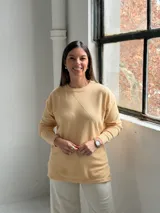 Sweater de punto color manteca con diseño de rombos en relieve, cuello redondo y mangas largas con puños ajustados.