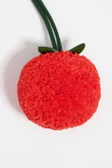 Charm para cartera color crudo con forma de cereza roja y hojas verdes.