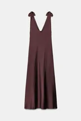 Vestido midi satinado color marrón, con escote en V y tirantes anchos ajustables con lazada en los hombros. Presenta cierre lateral con cremallera oculta.