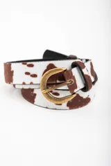 Cinto con estampado de vaca en tonos marrones y blancos, con hebilla metálica dorada envejecida.