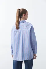 Camisa a rayas verticales blancas y marrones, de manga larga con puños abotonados, cuello camisero y botones frontales. Incluye un bolsillo en el pecho con bordado sutil.