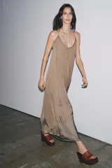 Vestido largo satinado color marrón topo, de escote redondo y tirantes finos cruzados en la espalda. Bajo asimétrico redondeado. Zara Woman Collection.