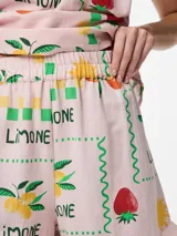 Short de tiro alto con cintura elástica y detalle de volados en el ruedo. Presenta un diseño estampado con motivos frutales y soles sobre fondo rosado, con un corte holgado y fresco.