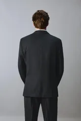 Blazer de corte regular confeccionada en lana de origen italiano, con diseño a cuadros sutiles. Presenta cuello con solapas de muesca, cierre frontal de un botón, bolsillos laterales con solapa y bolsillo en el pecho. Cuenta con aberturas en la espalda y forro interior.