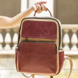 Mochila combinada color verde militar y mostaza, con doble bolsillo frontal y cierre de cremallera. Tiene asa de mano y correas regulables.