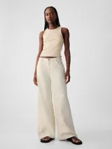 Jean de corte baggy y tiro medio, color crudo, con diseño de cinco bolsillos y cierre frontal con botón y cremallera.