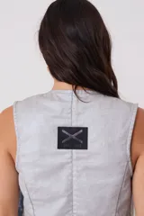 Chaleco de escote en V con cierre frontal mediante botones, bolsillos delanteros y estructura entallada en color plateado.