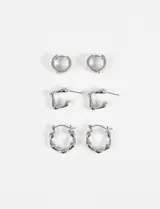Set de tres pares de aros plateados con diferentes diseños: aros tipo argolla con cierre a presión, aros tipo botón con forma irregular y aros tipo argolla con forma hexagonal irregular.